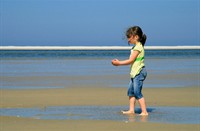 Meisje bouwt haar eigen wadden gebied met handjevol zand, Schiermonikoog